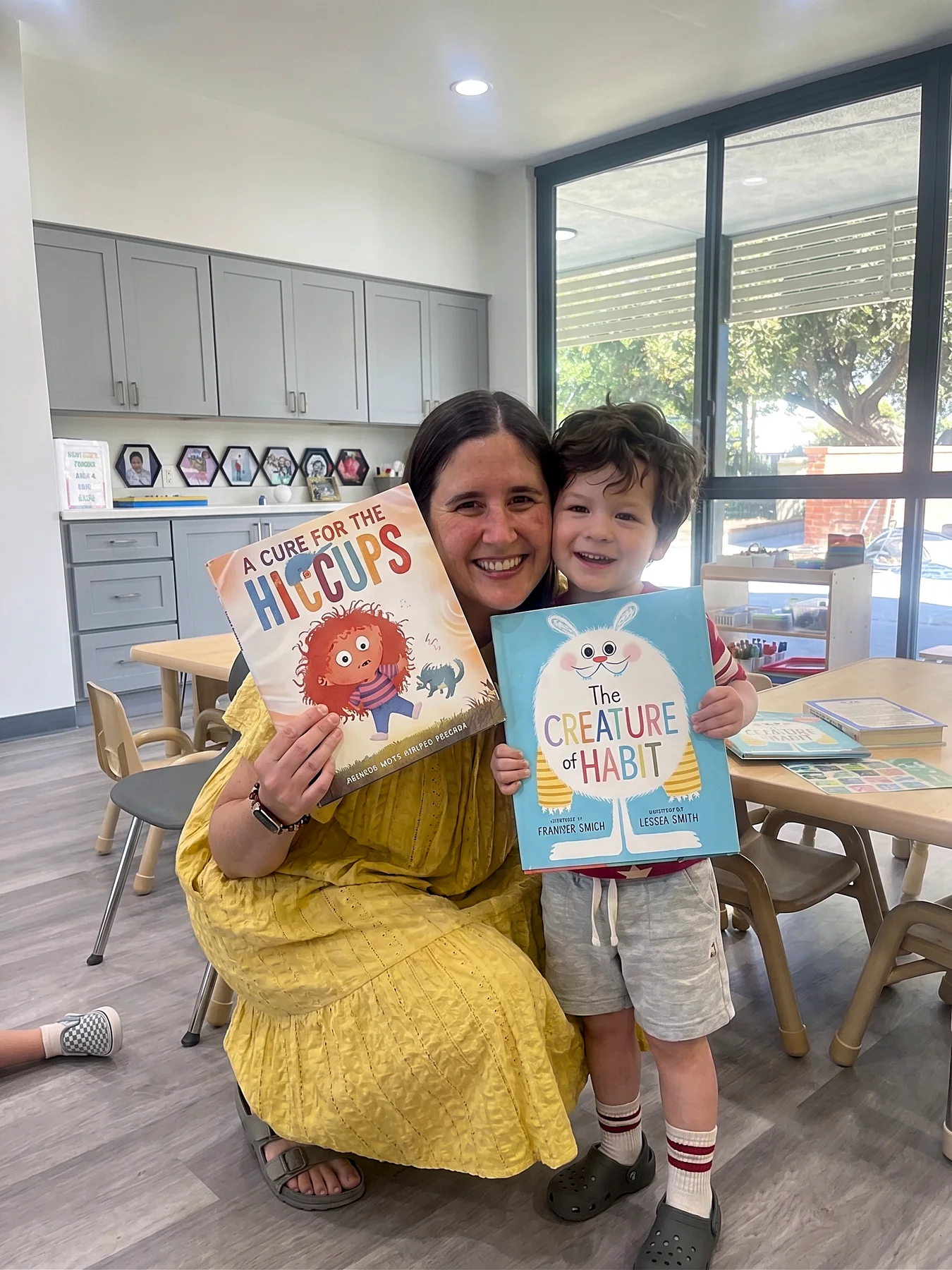 An adult and child holding picture books in a bright WCC classroom