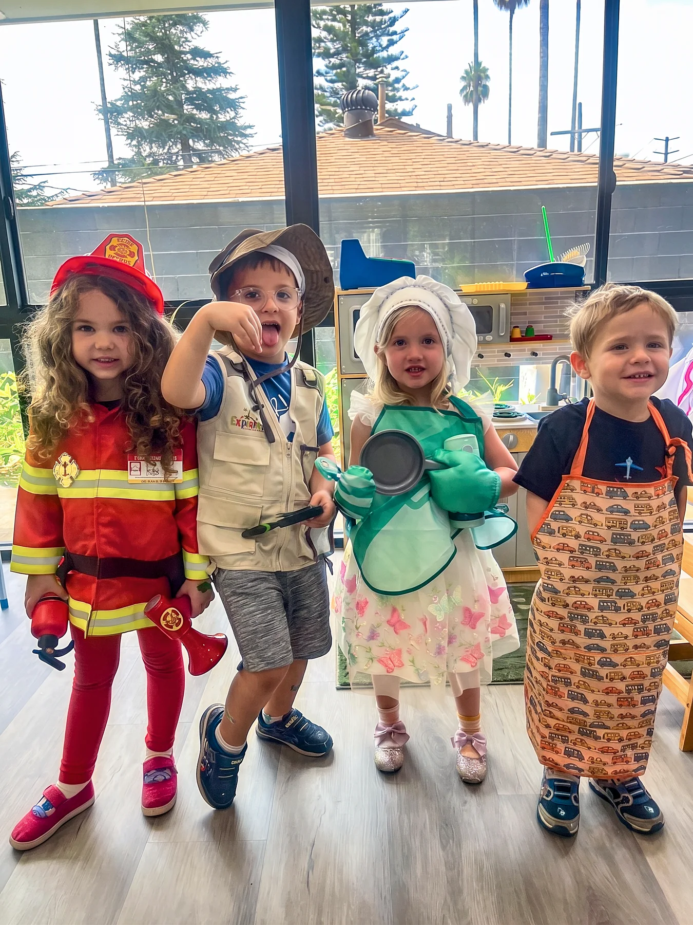 Four WCC children dressed for imaginative play as a firefighter, explorer, chef, and helper
