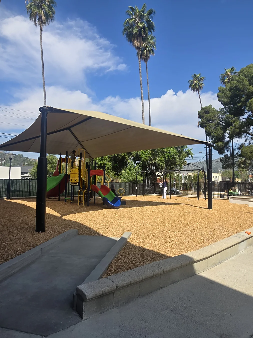 WCC's outdoor play area with a large shade canopy, climbing structures, and slides